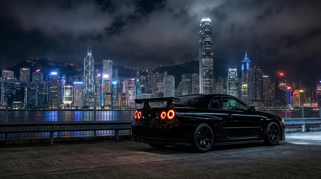 A black R34 Skyline GT-R at night in front of a city skyline.
